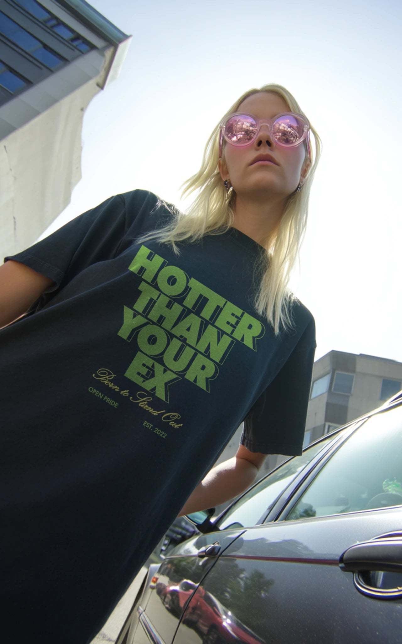 Junge Frau in Urbaner Umgebung trägt grünes, nachhaltiges Streetwear Shirt hotter than your ex