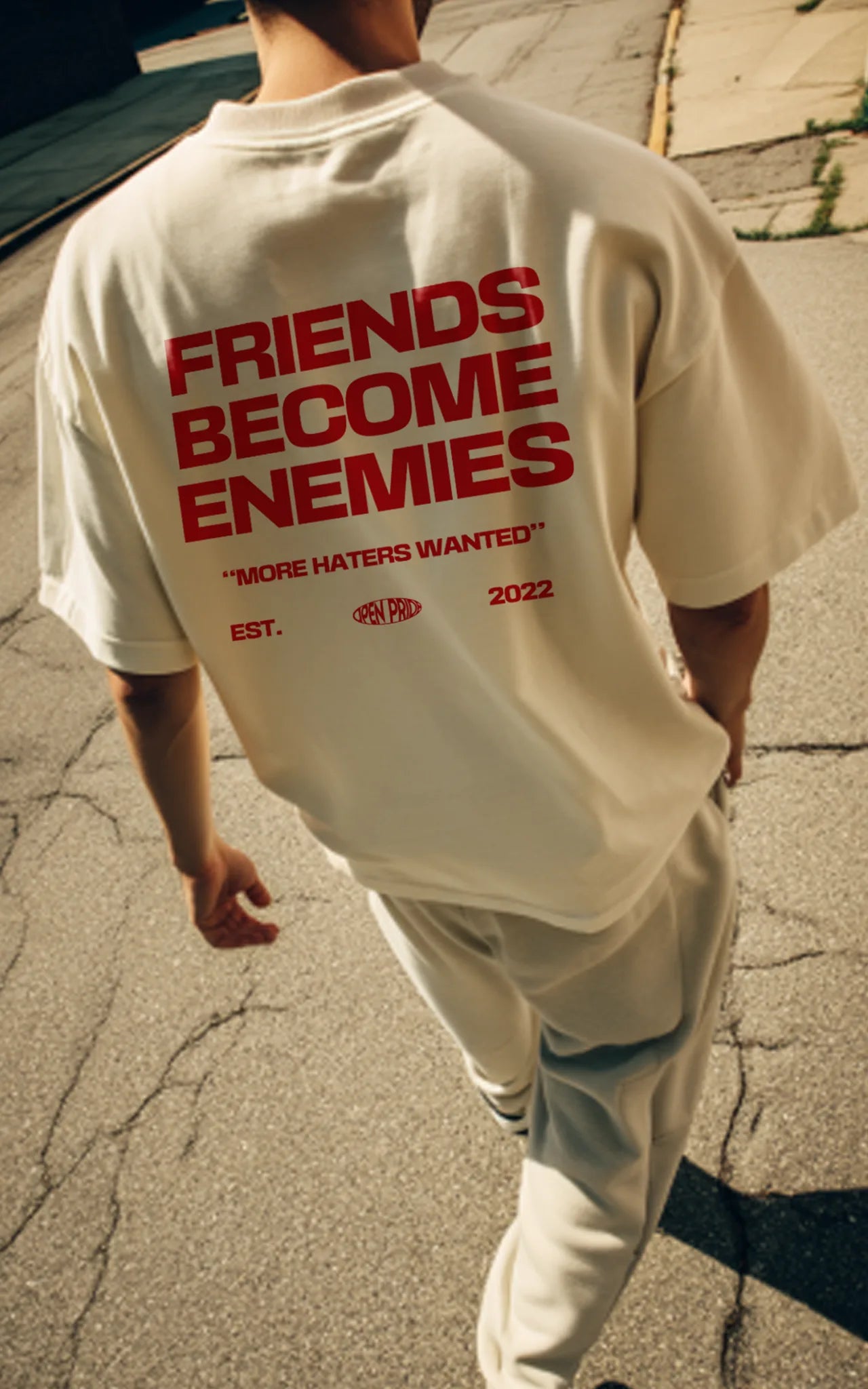 Junger Mann geht auf Straße und trägt Statement Streetwear Shirt Friends become enemies